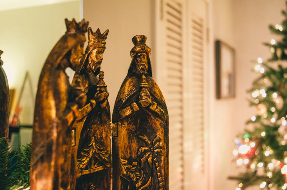 Beautiful traditional Three Kings figurines with blurred Christmas tree lights in the background.